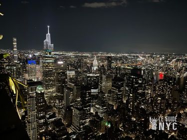 Vue de nuit sur le Chrysler Building au centre et l'insigne Pepsi-Cola à gauche